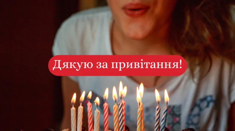 Чоловік дмухає свічки на торт з українським привітанням.