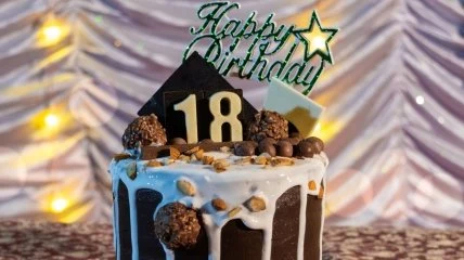 Торт на день народження з написом «18» та святковим декором.