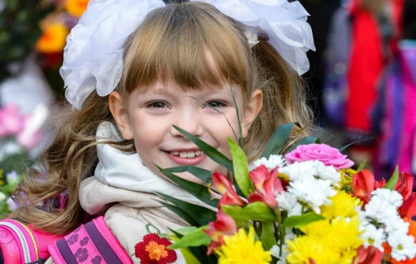 Дівчинка з квітами на святі для першокласників