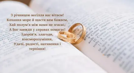 Два золоті кільця на відкритій книзі з привітанням