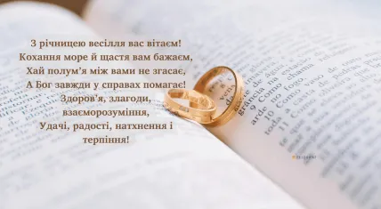 Два золоті кільця на відкритій книзі з привітанням.