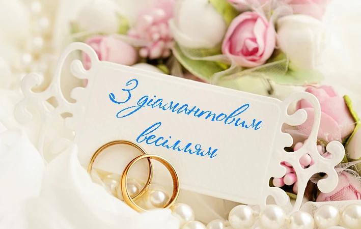 Дві золоті обручки серед перлин та квітів для вітання з діамантовим весіллям.